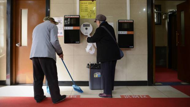 A woman gets toilet paper from a dispenser next to two unused automatic toilet paper dispensers that use facial recognition technology at a public toilet at the Temple of Heaven in Beijing on Tuesday. Face recognition technology flushes out China's toilet paper thieves