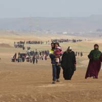 Displaced Iraqis flee their homes as Iraqi forces battle with Islamic State militants, in village of Badush northwest of Mosul, Iraq, Saturday. Iraqi forces find grave holding some 600 Shiite inmates executed by Islamic State