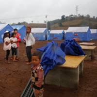 Refugees who fled fighting in neighboring Myanmar stand in a Chinese disaster relief tent camp in the town of Nansan, Yunnan province, China, March 12. Dozens killed in fresh clashes on Myanmar's China border