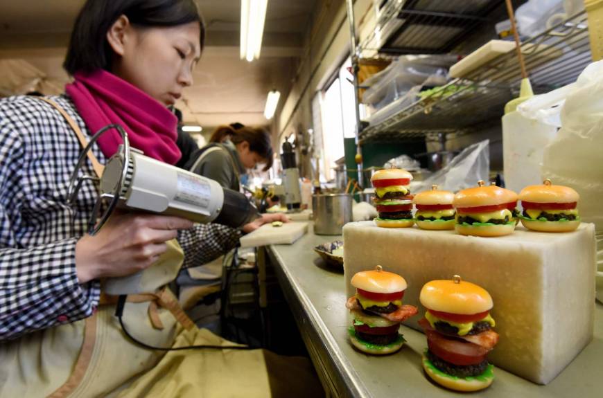 A craftswoman of Fake Food Hatanaka makes plastic hamburger earrings at the company