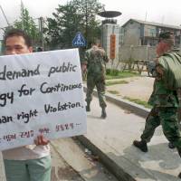 Outside the Yongsan U.S. Base in Seoul in 1996, U.S. soldiers pass by a student demanding the withdrawal of the U.S. military from South Korea. The protest was a response to the murder by a U.S. soldier of a prostitute in Tongduchon, 50 km north of Seoul. 'Comfort women' in South Korea who serviced U.S. forces seek justice