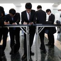 University students fill out registration forms at a job fair hosted by Mynavi Corp. in Tokyo in March. Amid labor crunch, firms woo graduates' parents to outdo rivals