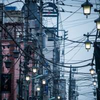 A web of cables is seen hanging from poles along a street in Hachioji, Tokyo. Koike's plan for Tepco to remove utility poles in Tokyo an Olympian task