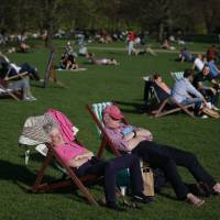 People relax in the sunshine in a park in central London on April 8. Pollution blamed on nitrogen dioxide-emitting diesel engines in the British capital is causing concern, and London Mayor Sadiq Khan has vowed to tackle the problem. In bid to ease pollution levels, London sets its sights on road traffic