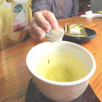 Hirokazu Kato, a tea wholesaler in Shizuoka Prefecture, shows how his firm’s tea bags can make a tea stem float vertically. Shizuoka firm promises good luck in every cup of its green tea