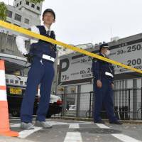 Police officers seal off a road near a parking lot in the city of Fukuoka where around ¥380 million ($3.5 million) in cash was allegedly stolen from a businessman on Thursday. Robbers seize suitcase with ¥380 million in cash from businessman in Fukuoka