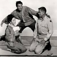 Best of intentions, worst of outcomes: Sakini (Marlon Brando) hovers over Lotus Blossom (Machiko Kyo) and Captain Fisby (Glenn Ford) in a publicity shot for “The Teahouse of the August Moon.” Brando's turn as an Okinawan 'host in a shell' haunts debate over 'yellowface'