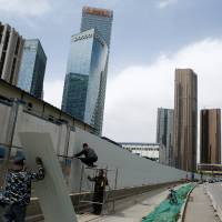 Workers build a fence at a construction site near recently erected office high-rises in Beijing on April 20. | REUTERS