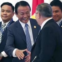 Finance Minister Taro Aso (second from left) greets Filipino Finance Minister Carlos Dominguez before a regional meeting of finance ministers in Yokohama on Friday. Aso warns regional finance chiefs to protect against capital outflows from Fed interest rate hikes