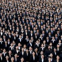 Newly-hired employees of Japan Airlines pose for photos during an initiation ceremony at a hangar of Haneda airport in Tokyo on April 3. Employment for university graduates hits record-high 97.6% amid labor shortage