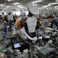 Robots work side by side with employees in the assembly line at a factory of Glory Ltd., a manufacturer of automatic change dispensers, in Kazo, Saitama Prefecture. Desperately short of labor, midsized firms plan to buy robots