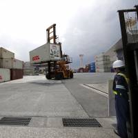 A security guard stands at the entrance of a transport container terminal in Tokyo. Japan posted a trade surplus for the third straight month in April, according to data released Monday. Exports propel Japan to third straight monthly trade surplus