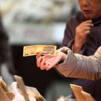 A shopper holds a bank note at a store in Tokyo’s Sugamo district, a popular area among elderly people. Due to the rapidly aging population, it is predicted that the amount of money in sleeping accounts and cash left behind by people who die without heirs will increase. Japan waking up to the problems of sleeping cash