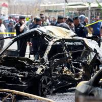 The wreckage of a car is seen at the site of a car bomb attack near a government office in the Karkh district in Baghdad on Tuesday. Islamic State-claimed suicide blasts kills 27 in Baghdad as battle to liberate Mosul turns cautious