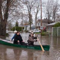 Residents in a canoe paddle on the flooded streets in Pierrefonds, Quebec, on Sunda. More than 130 communities in the province have been hit by the flooding, with an estimated 1,500 homes affected and 850 people forced to evacuate. Canada deploys more troops as flood threat increases, over 1,000 evacuate