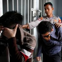 Two Indonesian men, who were later sentenced to 85 lashes of the cane for having sex together, are escorted by police into an Islamic court in Banda Aceh, Aceh province, Indonesia, Wednesday. Aceh Shariah court in a first sentences gay pair to caning, undermining Indonesia's moderate image
