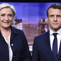 French presidential election candidate for the far-right Front National party, Marine Le Pen, and French presidential election candidate for the En Marche ! movement, Emmanuel Macron, pose prior to the start of a live broadcast face-to-face televised debate in La Plaine-Saint-Denis, north of Paris, Wednesday as part of the second round election campaign. Le Pen and Macron trade insults on TV in heated final French debate
