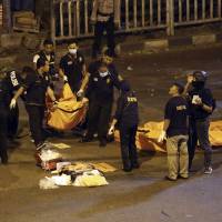 Police officers carry a body bag from the site where explosions reportedly went off near a bus terminal in Jakarta Thursday. A suspected suicide bombing near a bus terminal in Indonesia’s capital Wednesday night killed a policeman and injured nine other people, including four officers, police said. Two suicide bombers kill three police officers outside Jakarta bus terminal