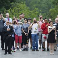 Visitors stand as “Taps” is played during a wreath laying ceremony at the grave of the late President John F. Kennedy to mark the 100th anniversary of his birth, at Arlington National Cemetery in Arlington, Virginia, Monday. Kennedy was born May 29, 1917. Thousands turn out to remember JFK on his 100th birthday