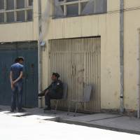 A policeman sits near the gate of a foreign guest house in Kabul Sunday. An Afghan official says that a German woman along with her Afghan security guard have been killed in the guest house. Two killed, one kidnapped as gunmen storm Kabul guest house