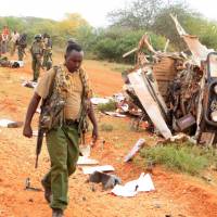 A Kenyan security person walks past a police vehicle damaged by a blast killing Kenyan police officers at the Garissa county, eastern Kenya, Wednesday. Separate bombs kill eight Kenya police officers as al-Shabab steps up attacks