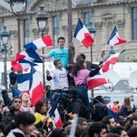 Supporters of Emmanuel Macron, French presidential candidate, wave French flags while reacting as vote projections are announced in the second round of the French presidential election in Paris Sunday. Macron pledged to unite France’s rifts after his victory over Marine Le Pen in the presidential election, saying that he’ll work to address the concerns that were exposed during one of the most divisive campaigns of recent history. World's media issue positive verdict on Macron win but also express caution