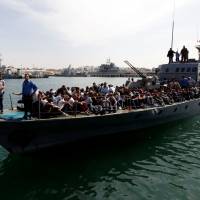 Migrants arrive by boat at a naval base after they were rescued by the Libyan coast guard in the coastal city of Tripoli Wednesday. Libya coast guard returns 300 migrants to Tripoli after altercation with NGO ship