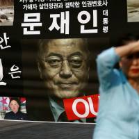 A woman walks past a placard opposing new South Korean President Moon Jae-in’s policy on North Korea in Seoul on Thursday. First liberal rule in decade unlikely to bring swift changes to South Korea