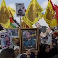 Protesters carry pictures of jailed Palestinian prisoners during a rally supporting Palestinian prisoners in Israeli jails, who have been on an open-ended hunger strike for the past 17 days, in the West Bank city of Ramallah Wednesday. Thousands rally in West Bank to support Palestinian prisoners' hunger strike