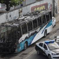 The shell of a bus is parked on the side of a road, allegedly set on fire by drug traffickers, in Rio de Janeiro Tuesday. Several public buses and cargo trucks were torched in Rio de Janeiro on Tuesday in what Brazilian military police said was likely gang retaliation for a large anti-drug operation. Rio police kill two suspected drug gang members amid retaliatory clashes, bus torchings