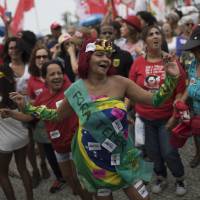 A woman wearing a costume that reads in Portuguese “Temer out” dances during a protest over Brazil’s President Michel Temer at Copacabana beach in Rio de Janeiro Sunday. People gathered on Copacabana beach ahead of a concert by Brazilian musical performers calling for new presidential elections, while pressure mounts on the country’s leader to resign amid corruption allegations. Top Brazilian musicians stage protest concert in Rio, demanding president's ouster