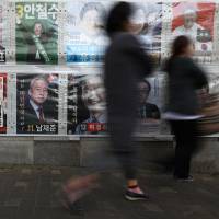 Pedestrians in the port city of Incheon, west of Seoul, on Saturday walk past campaign posters showing South Korean presidential candidates. Election poised to bring South Korea change following months of political upheaval