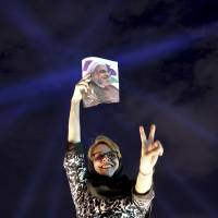 A supporter of Iranian President Hassan Rouhani holds a poster of him while celebrating his victory in the presidential election in Tehran on Saturday. Iran's Rouhani finds himself under U.S. pressure after election win