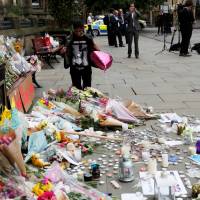 An Ariana Grande fan stands next to tributes left for the victims of an attack on concert goers at Manchester Arena on Wednesday. Japanese residents of Manchester shaken by terrorist attack