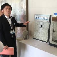 An official from the Agency for Natural Resources and the Nuclear Waste Management Organization of Japan shows a model of a proposed underground burial facility for nuclear waste during a town hall meeting in Toyama on May 20. Nuclear storage crisis grows as reactor restarts continue