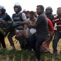 Bangladeshi police officials carry an injured fireman during a raid on a Islamic militant hideout in Rajshahi on May 11. The slippery slope of appeasement in Bangladesh
