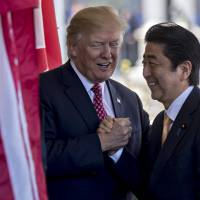 U.S. President Donald Trump greets Prime Minister Shinzo Abe as he arrives at the White House on Feb. 10. Abe has delivered much more on longstanding demands by the U.S. than all of his predecessors combined, shifting Japan toward a beefed-up military role in the alliance. Under Abe, are we heading toward a beautiful Japan or an ugly future?