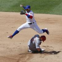 Chicago’s Javier Baez jumps over Cincinnati’s Tucker Barnhart after forcing him out in the fifth inning at second base on Thursday. Baez hits grand slam, Bryant homers as Cubs beat Reds 9-5