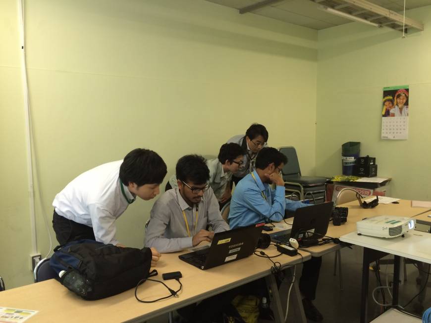 Indian interns Shubham Jain and Yash Ubale programming as their Fujifilm Software Co. colleagues look on.