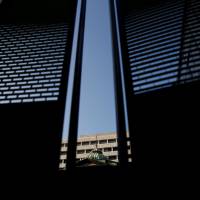 The Bank of Japan building is seen between walls at a construction site in Tokyo. BOJ is more minnow than whale in Japan stocks, SocGen finds