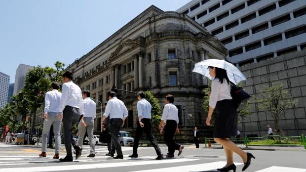 Office workers walk past the Bank of Japan building in Tokyo on Friday. BOJ keeps policy unchanged amid growing pressure to discuss stimulus exit plan
