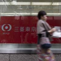 A pedestrian walks past a branch of the Bank of Tokyo-Mitsubishi UFJ Ltd., a unit of Mitsubishi UFJ Financial Group Inc. (MUFG), in Tokyo in November. MUFG is considering eliminating about 10,000 positions — about 7 percent of its workforce — over a decade. MUFG's drastic staff restructure set to cut 10,000 positions in 10 years