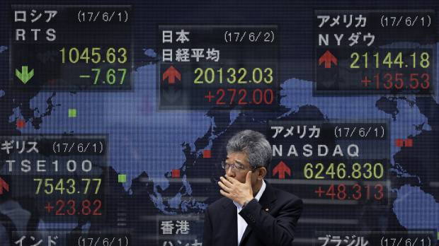 A pedestrian stands in front of a stock price display at a securities firm in Tokyo Friday. The Nikkei average rose above 20,000 points to close at a 22-month high. Uncertainty over U.S. policy might cap gains in Japan stocks