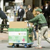A Yamato Transport worker handles parcels in the Tokyo’s Ginza district in March. KYODO Yamato modifies delivery time slots to ease driver burden