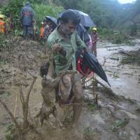 A man carries the carcass of a goat as rescuers search amid the mud after a landslide in Bandarban, Bangladesh, on Tuesday. Death toll in Bangladesh landslides rises to at least 132