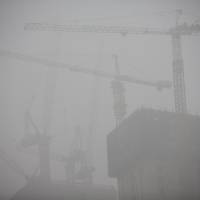 Construction cranes stand shrouded in haze in Beijing. New Beijing chief vows to finally win fight against pollution