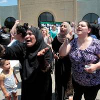 Women react as they talk about family members seized on Sunday by Immigration and Customs Enforcement agents during a rally outside the Mother of God Catholic Chaldean church in Southfield, Michigan, Monday. Detroit-area roundup of Chaldeans with old deportation orders spurs protest