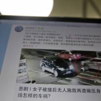 A website shows a frame from a video of a woman as she is run over by a car at a traffic junction displayed on a computer in Beijing on Saturday. The grainy video of the traffic accident in the city of Zhumadian surfaced on Chinese social media last week, the initial reaction was one of outrage directed at the more than 40 pedestrians and drivers who passed within meters of the woman, all failing to offer help. China ponders public morality after video of gruesome death