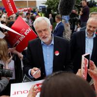 Jeremy Corbyn, leader of Britain’s opposition Labour Party, signs placards at a campaign event in Reading, England, Wednesday. Written off as a no-hoper, socialist U.K. Labour leader Corbyn gaining ground, crowds ahead of polls