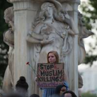 People hold up signs during a vigil in Washington Tuesday for Nabra Hassanen, a 17-year old Muslim girl who was killed in an alleged road rage incident on Sunday. Thousands attend slain Muslim girl's funeral in Virginia